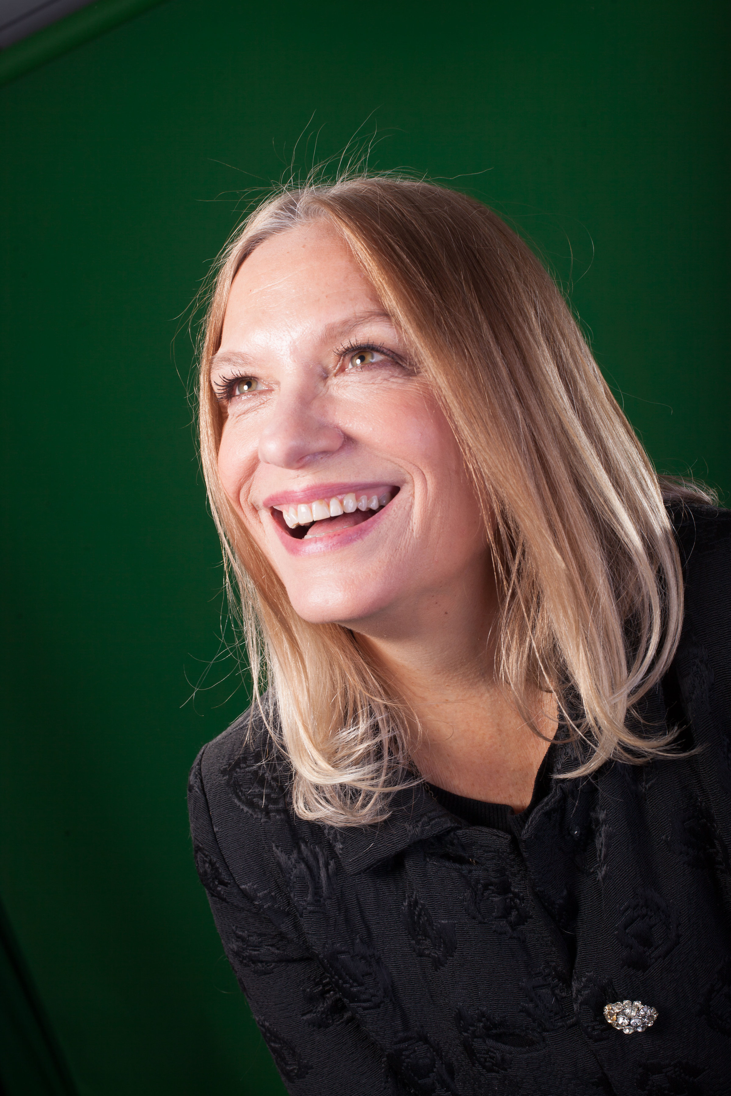 [Image Description: A headshot of a smiling woman with straight blonde hair. She is leaning to the left of the photo and looking up.]]