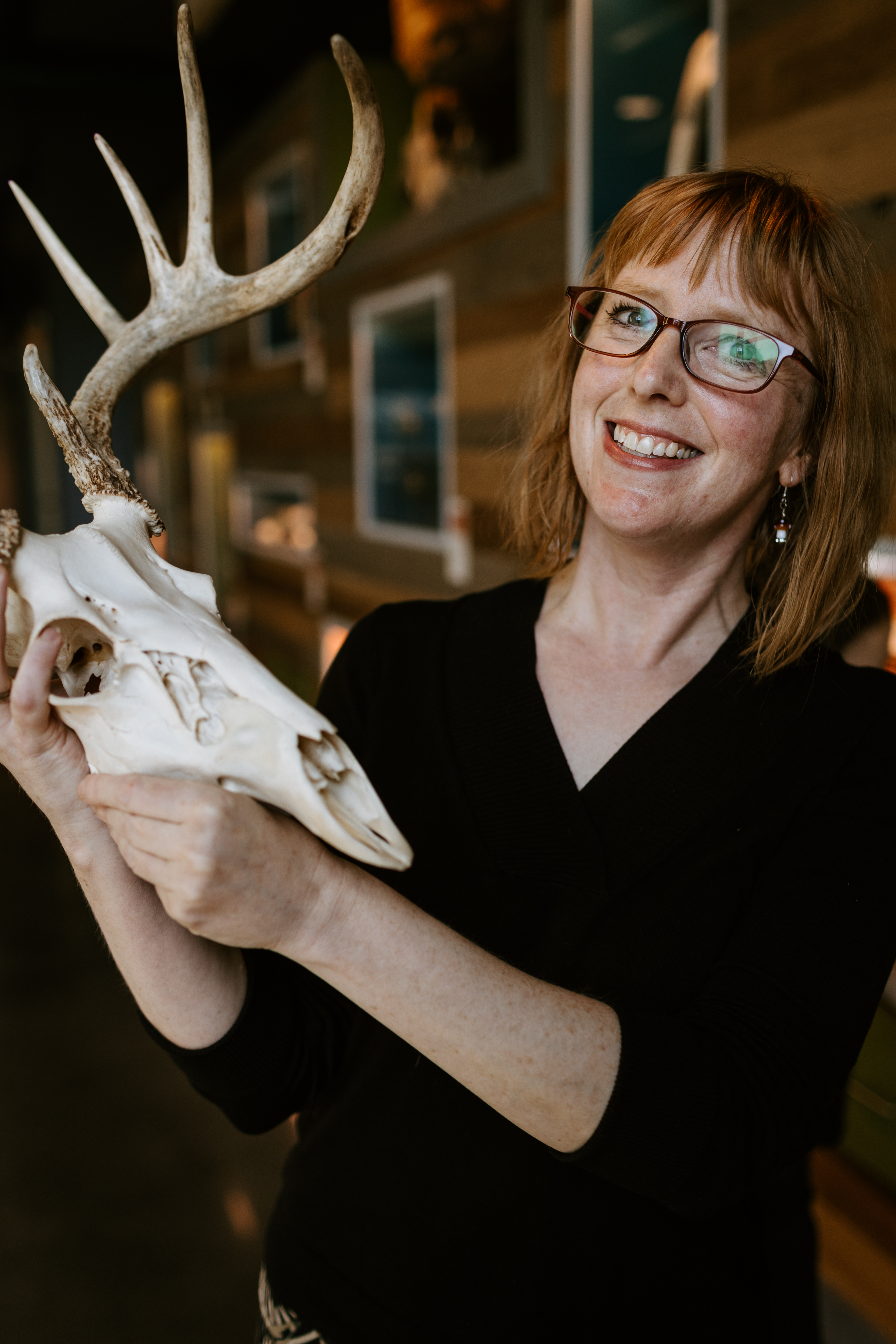 Emma Allen, a woman with red hair and glasses, holds an animal skull