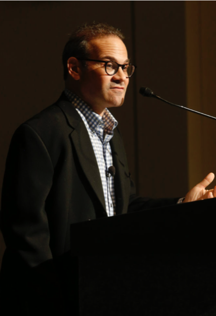 Jonathan Kaufman, a white man with black glasses, stands at a podium